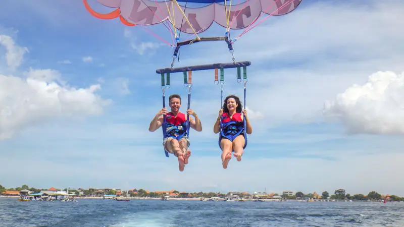 First-time tandem parasailers smiling calmly over Bali’s ocean.