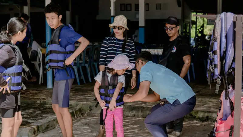 Staff member securing a guest’s life jacket before parasailing