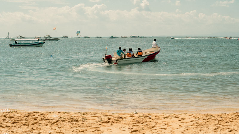 Parasailing participants being transferred by boat from the beach to the launch area in Tanjung Benoa, Bali