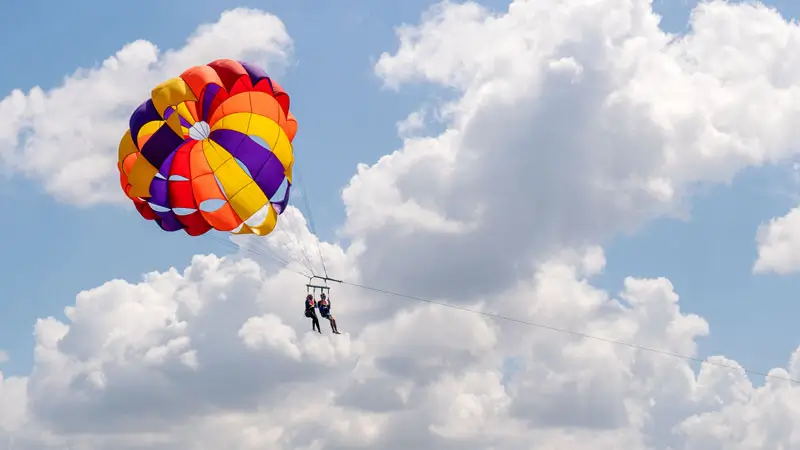 Parent and child doing tandem parasailing in Bali sky