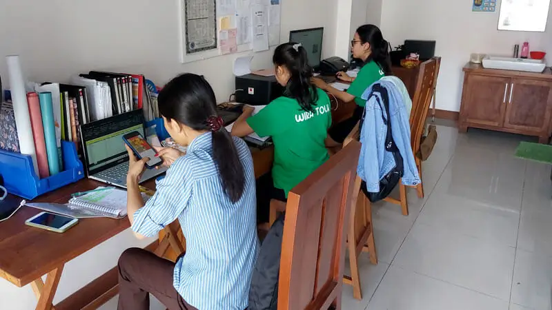 Wira Tour Bali team processing water sports bookings on desktop and phone