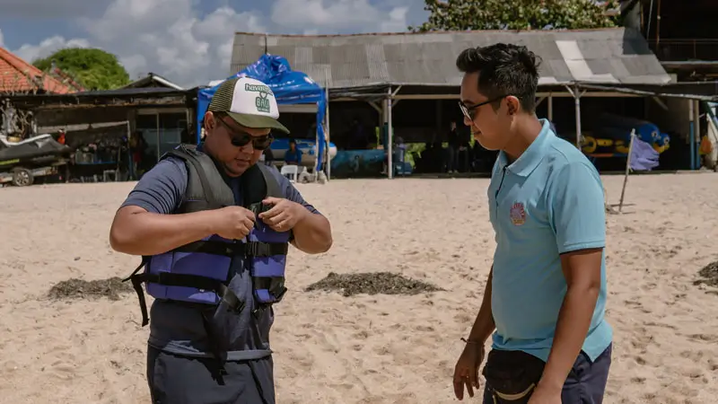 Wira Tour Bali staff helping guest feel safe before parasailing in Tanjung Benoa.
