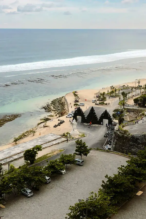 Overlook of Melasti Beach entrance gates, access road and beach-level parking for wayfinding.
