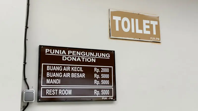 Toilet and shower donation sign near beach-level parking.