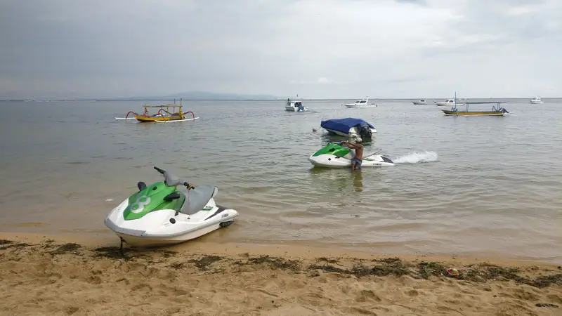 Sanur jet ski in shallow water near the beach with boats in the background