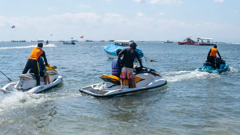 Riders depart from the shoreline with instructors on personal watercraft