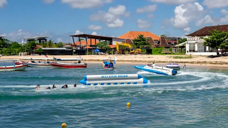 Riders in the water after a banana boat flip in Bali, waiting to reboard.