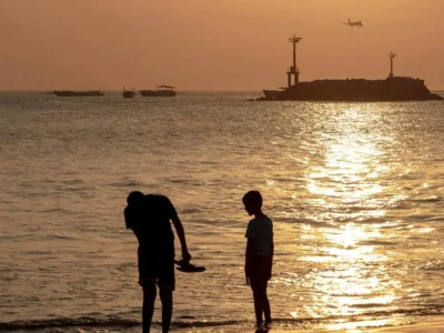 Jimbaran Bali with kids at sunset on calm beach with passing plane near airport