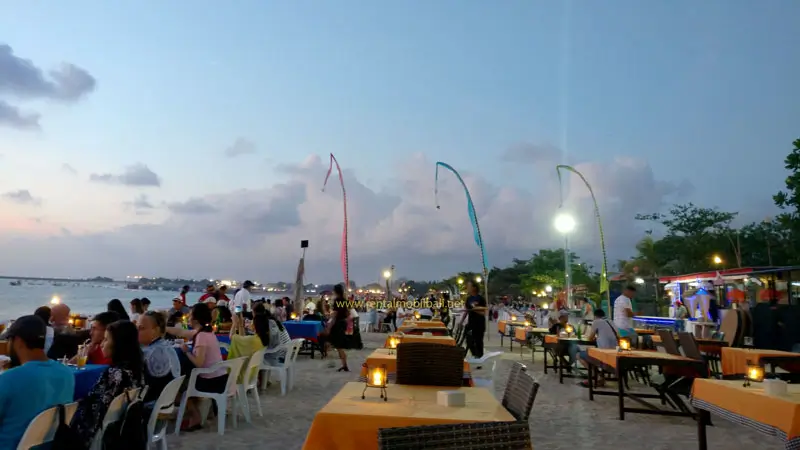 Seafood cafes with tables on the sand at sunset