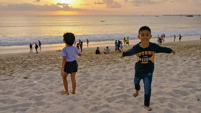 Children playing on Jimbaran Beach at sunset with calm evening atmosphere