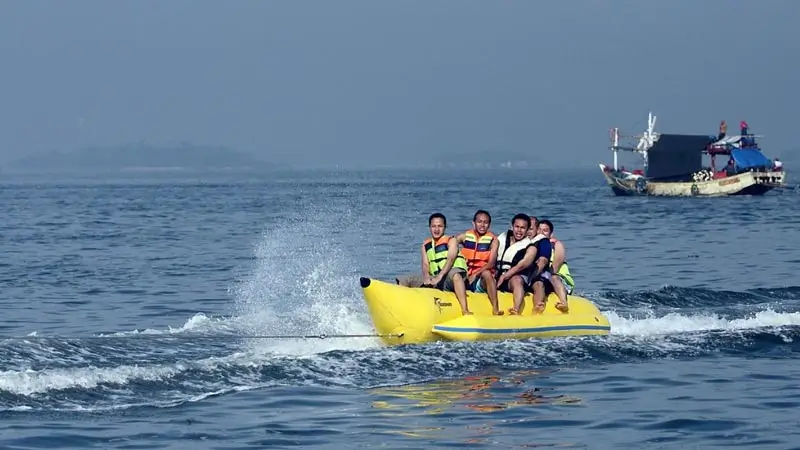 Sanur Banana Boat ride with five riders on yellow raft wearing life jackets on calm water
