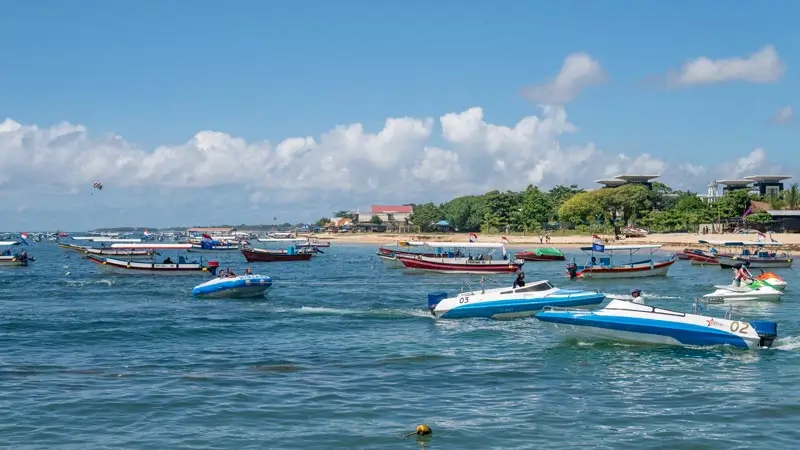 Busy Tanjung Benoa watersports corridor with banana boats and speedboats