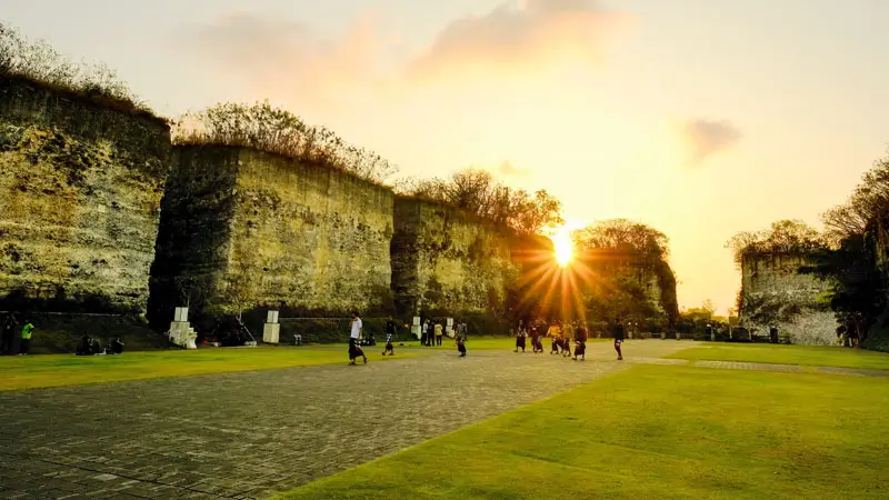 Visitors walking across Lotus Pond GWK plaza at golden hour in Bali