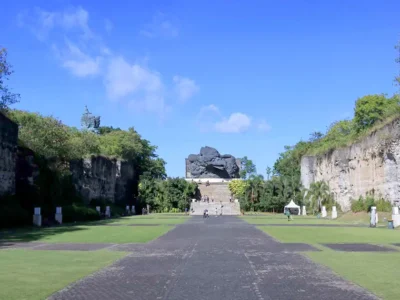 Daytime view of Lotus Pond GWK Bali with limestone walls and Garuda statue in the distance