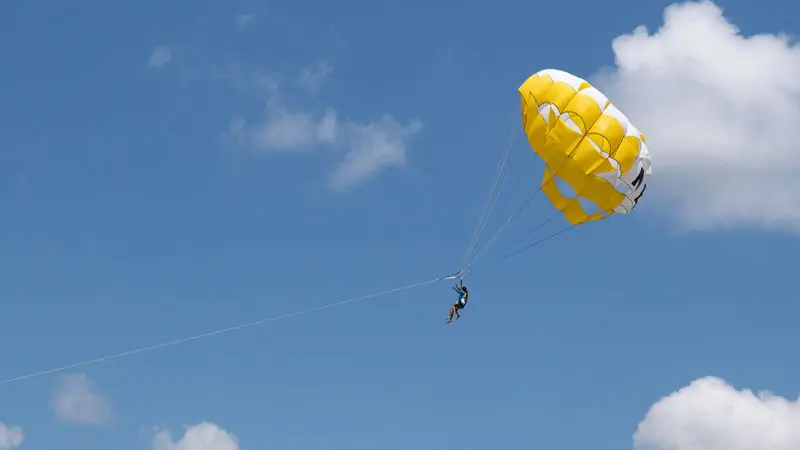 Parasailing above Tanjung Benoa on a clear day, an example of a paid activity add-on