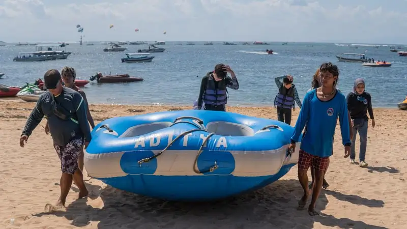 Aditya Water Sport crew carrying the donut tube on the beach