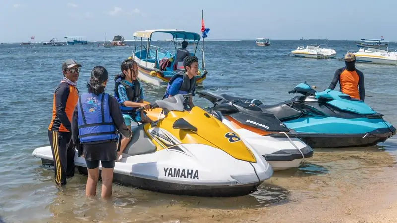 Water sports for kids in Bali: instructor helping kids onto a jet ski