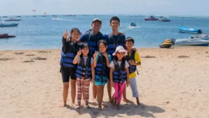 Water sports for kids in Bali: family photo in life jackets on the beach