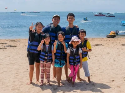 Water sports for kids in Bali: family photo in life jackets on the beach