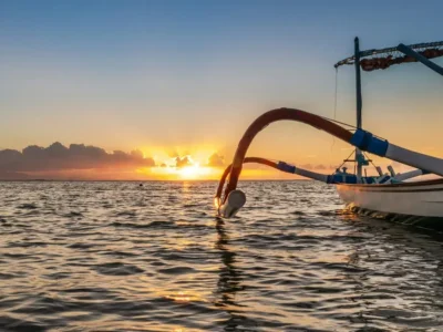 Sunrise over a calm sea with a traditional outrigger boat, peaceful mood