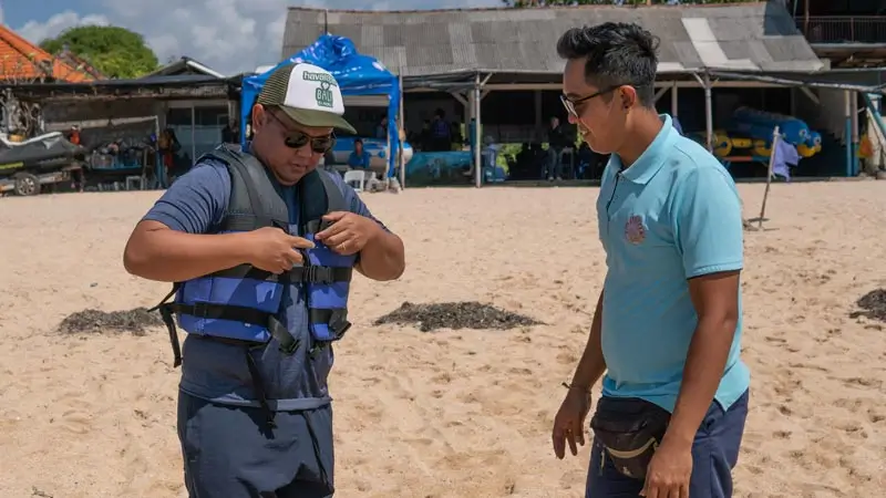 Staff checks a life jacket fit before a water sports session