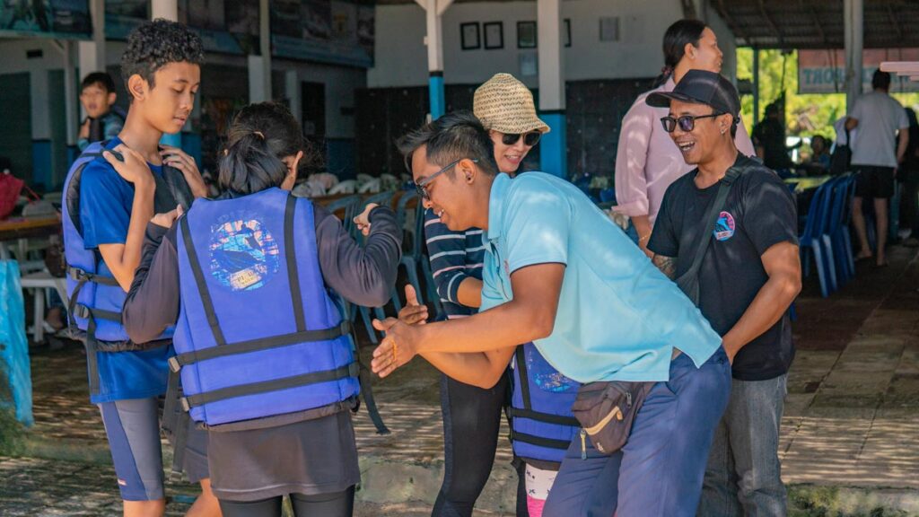 Staff giving a safety briefing to guests wearing life jackets before activities.