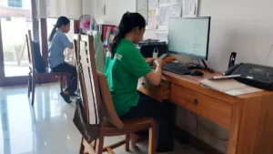 Wira Tour Bali team replying to WhatsApp booking messages at the office desk.