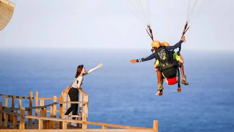 Tandem paragliding over the coastline as a Bali adventure activity