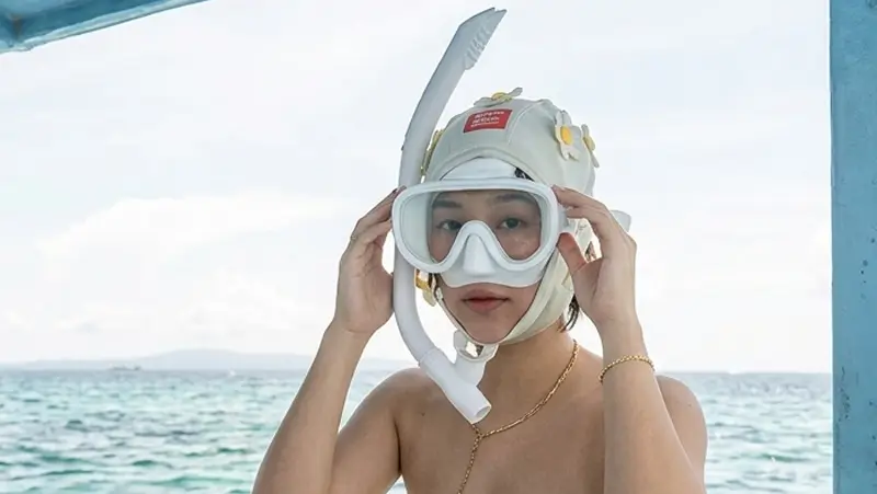 Guest adjusting a mask while sitting on a boat