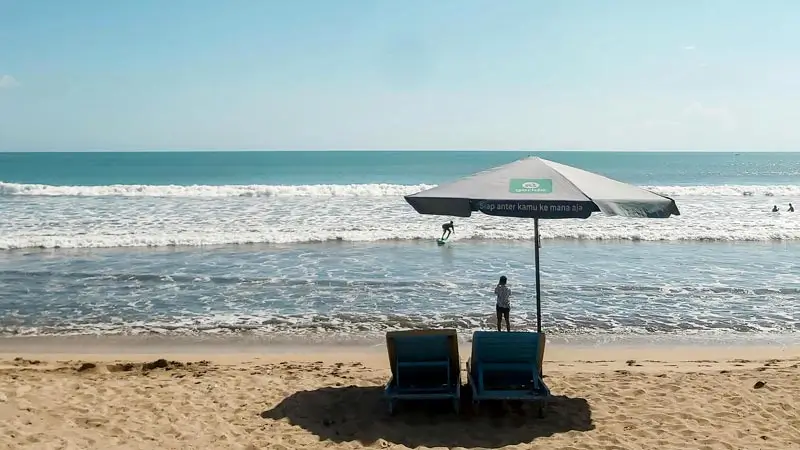 Beach chairs and umbrella facing the waves on Legian Beach