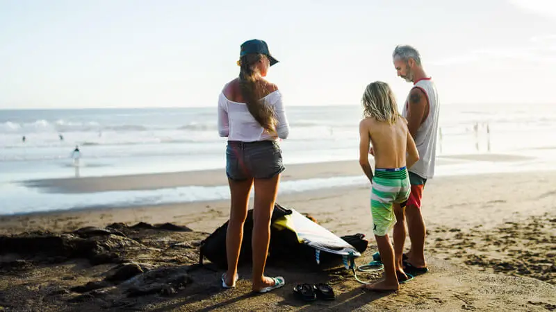 Family preparing for surfing near the shoreline at Legian Beach Bali