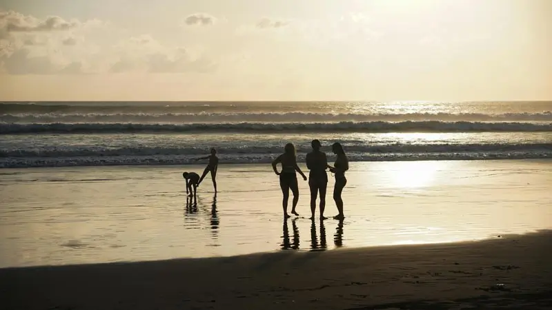 Late afternoon walk with silhouettes on wet sand