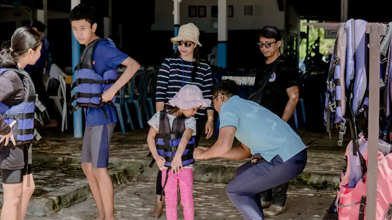 On-site staff helps a child adjust a life jacket before activity